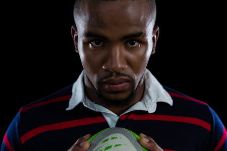 Close up portrait of sportsman holding rugby ball against white backgroundの写真素材
