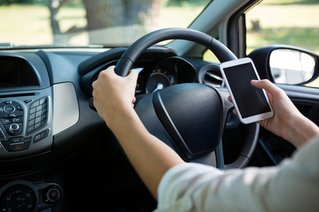 Mid-section of woman using mobile phone while driving a carの写真素材