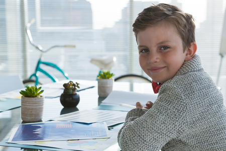 Portrait of boy as business executive smiling while sitting in officeの写真素材