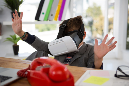 Boy as business executive using virtual reality headset in officeの写真素材