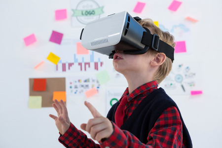 Boy as business executive using virtual reality headset in office