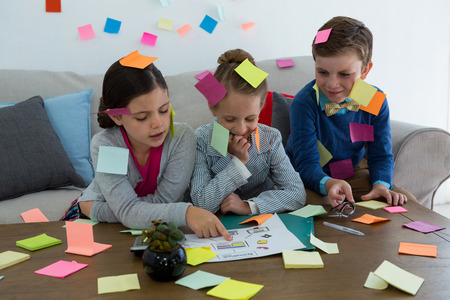 Kids as business executives playing with sticky notes in officeの写真素材