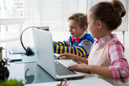 Kids as business executive interacting while using laptop in office