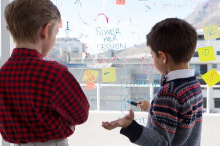 Kids as business executives discussing over whiteboard in office