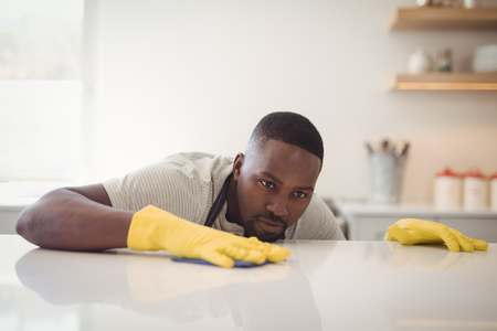 Man cleaning the kitchen worktop at homeの写真素材