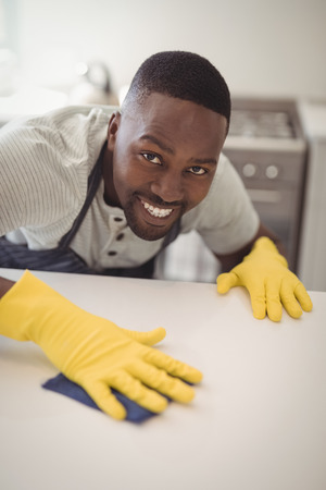 Portrait of smiling man cleaning the kitchen worktop at homeの写真素材