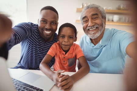 Happy multi-generation family looking at camera in kitchen