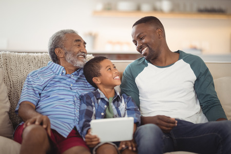 Smiling multi-generation family sitting together on sofa in living roomの写真素材