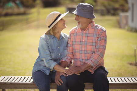 Smiling senior couple looking at each other while sitting on a benchの写真素材