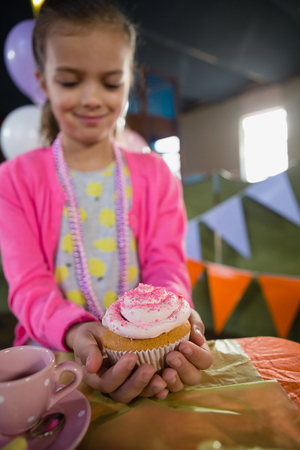 Birthday girl holding a cupcake at home