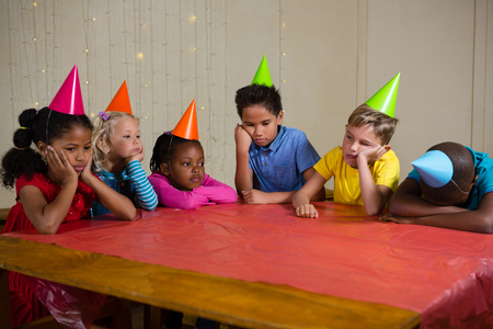 Tired children sitting at table during birthday partyの写真素材