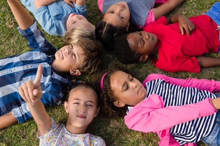 Overhead view of children with arms raised lying on field in yardの写真素材