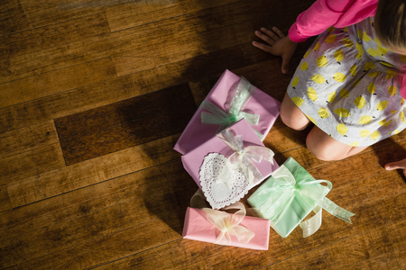 Girl sitting with gift boxes on wooden floor at homeの写真素材