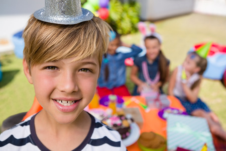 Close up portrait of happy boy with friends in background during birthdayの写真素材