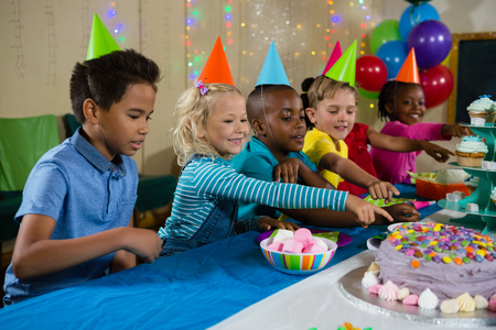 Kids pointing on cake at table during birthday partyの写真素材