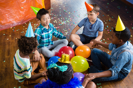 High angle view of children sitting with holding hands during birthdayの写真素材