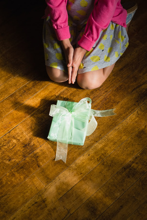 Girl sitting with gift box on wooden floor at homeの写真素材