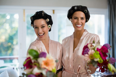 Portrait of bride and bridesmaids standing with bouquet at homeの写真素材