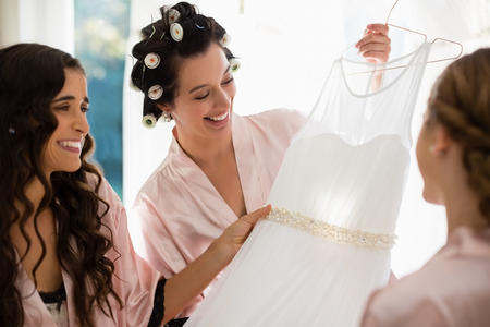 Smiling women looking at wedding dress at homeの写真素材
