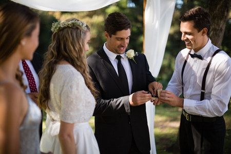 Waiter giving engagement ring to groom in parkの写真素材