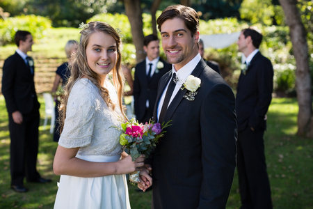 Portrait of happy bride and groom standing in parkの写真素材