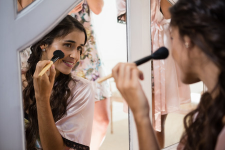 Bride applying her makeup doing her wedding preparation at homeの写真素材
