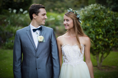 Smiling wedding couple standing face to face in gardenの写真素材