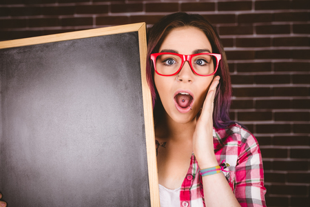 Portrait of shocked woman holding slate against brick wallの写真素材