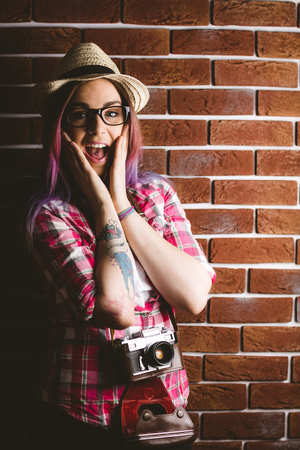 Portrait of shocked woman in spectacles against brick wallの写真素材