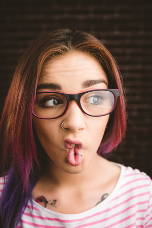 Thoughtful woman making facial expression against brick wallの写真素材