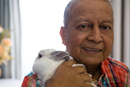 Close up portrait of senior man holding rabbit at nursing home