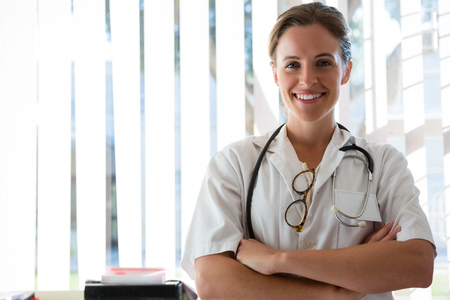 Portrait of confident female doctor with arms crossed standing in nursing homeの写真素材