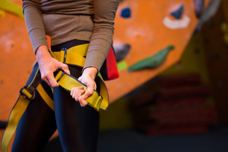 Mid section of woman wearing safety harness in fitness studio
