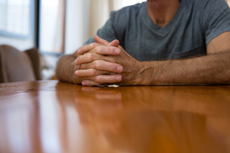 Midsection of senior man sitting at table in nursing homeの写真素材