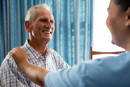 Happy senior man talking to female doctor in retirement homeの写真素材