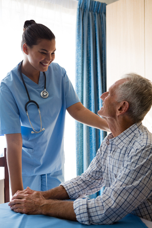 Smiling female doctor consoling senior man in retirement homeの写真素材