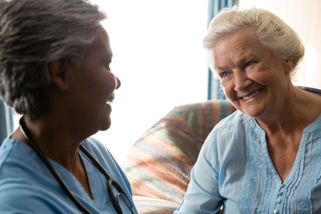 Smiling nurse talking to senior patient in nursing homeの写真素材