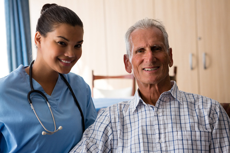 Portrait of smiling female doctor with senior man sitting in nursing homeの写真素材