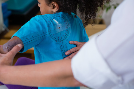 Physiotherapist examining girl patients back with goniometer in the clinicの写真素材