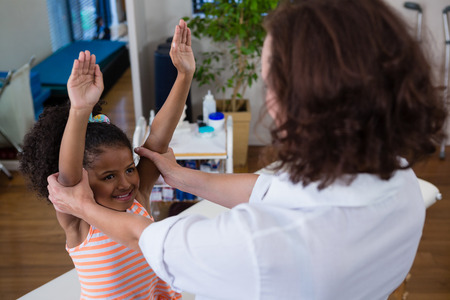 Physiotherapist giving hand massage to a girl in clinicの写真素材