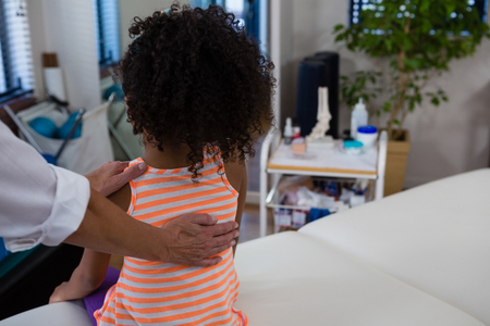Physiotherapist giving back massage to girl patient in clinicの写真素材