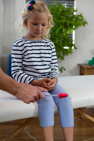 Doctor examining reflexes of patient knee in clinicの写真素材