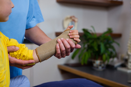 Physiotherapist giving hand massage to girl patient in clinicの写真素材