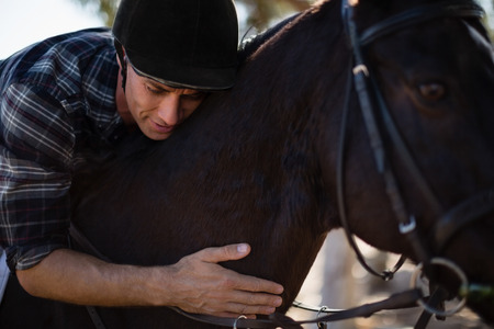 Male jockey riding horse in the ranch on a sunny dayの写真素材