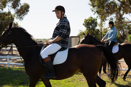 Two male friends riding horse in the ranch on a sunny day