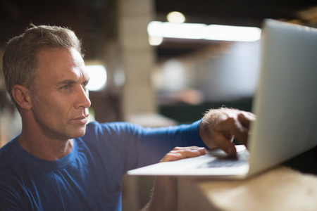 Mature man using laptop in the stable