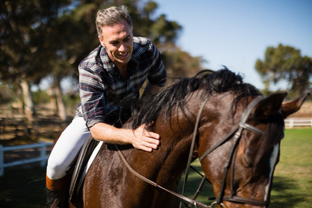 Man riding a horse in the ranch on a sunny dayの写真素材