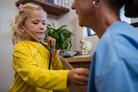 Cute little girl using stethoscope in hospitalの写真素材
