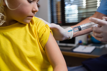 Physiotherapist injecting girl patient in clinicの写真素材