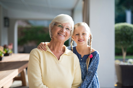 Smiling granddaughter and grandmother together in a deck shade on a sunny day